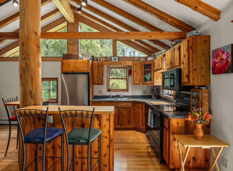 Experience rustic charm in this spacious kitchen featuring warm wood cabinetry and a striking log beam accent.