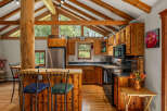 Experience rustic charm in this spacious kitchen featuring warm wood cabinetry and a striking log beam accent.
