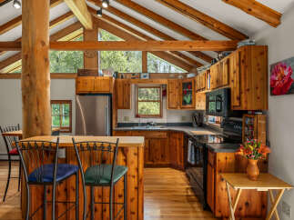 Experience rustic charm in this spacious kitchen featuring warm wood cabinetry and a striking log beam accent.