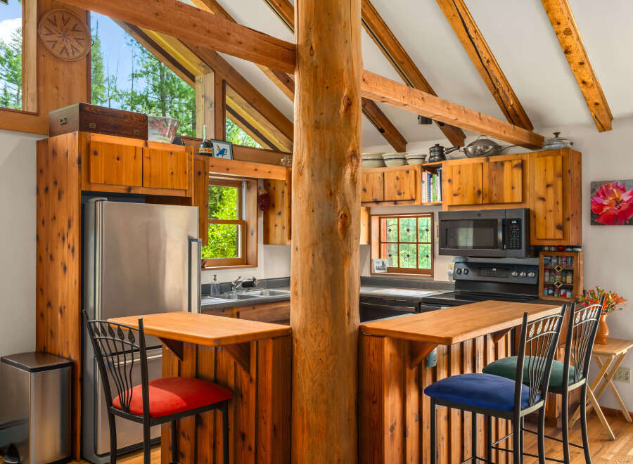 Experience rustic charm in this cozy log cabin kitchen, featuring warm wooden cabinetry and exposed beams that create a natural, inviting atmosphere.