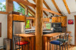 Experience rustic charm in this cozy log cabin kitchen, featuring warm wooden cabinetry and exposed beams that create a natural, inviting atmosphere.