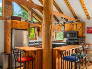 Experience rustic charm in this cozy log cabin kitchen, featuring warm wooden cabinetry and exposed beams that create a natural, inviting atmosphere.