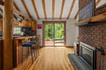 Experience rustic charm in this cozy cabin kitchen featuring warm wood cabinetry, a breakfast bar with seating, and a stunning view of the surrounding greenery through a large sliding glass door.
