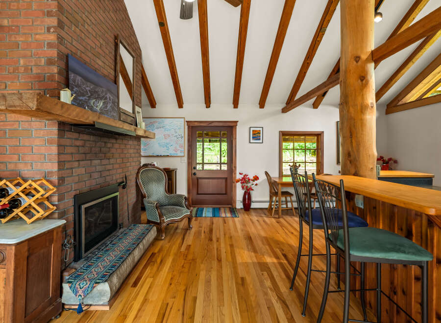 Experience rustic charm in this inviting living space, featuring a striking brick fireplace and exposed wooden beams that add warmth and character.