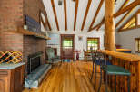 Experience rustic charm in this inviting living space, featuring a striking brick fireplace and exposed wooden beams that add warmth and character.