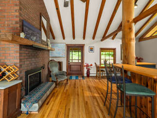 Experience rustic charm in this inviting living space, featuring a striking brick fireplace and exposed wooden beams that add warmth and character.