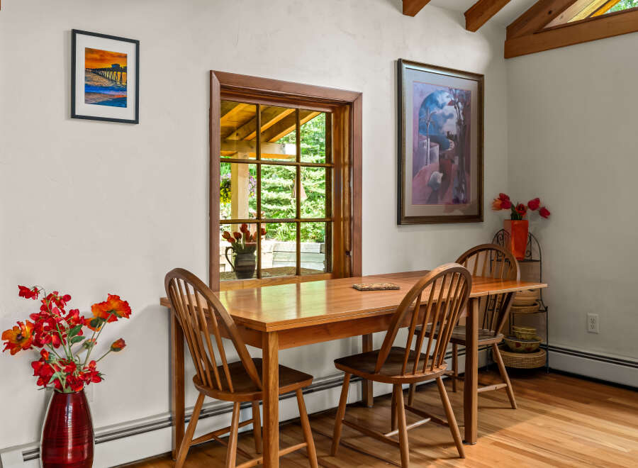 Enjoy intimate meals in this charming dining area, featuring a warm wooden table and chairs bathed in natural light from a large window.