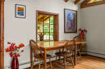 Enjoy intimate meals in this charming dining area, featuring a warm wooden table and chairs bathed in natural light from a large window.