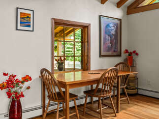 Enjoy intimate meals in this charming dining area, featuring a warm wooden table and chairs bathed in natural light from a large window.
