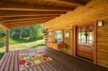Step onto the inviting wooden porch of this charming log cabin, perfect for enjoying the serene natural surroundings.