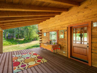 Step onto the inviting wooden porch of this charming log cabin, perfect for enjoying the serene natural surroundings.