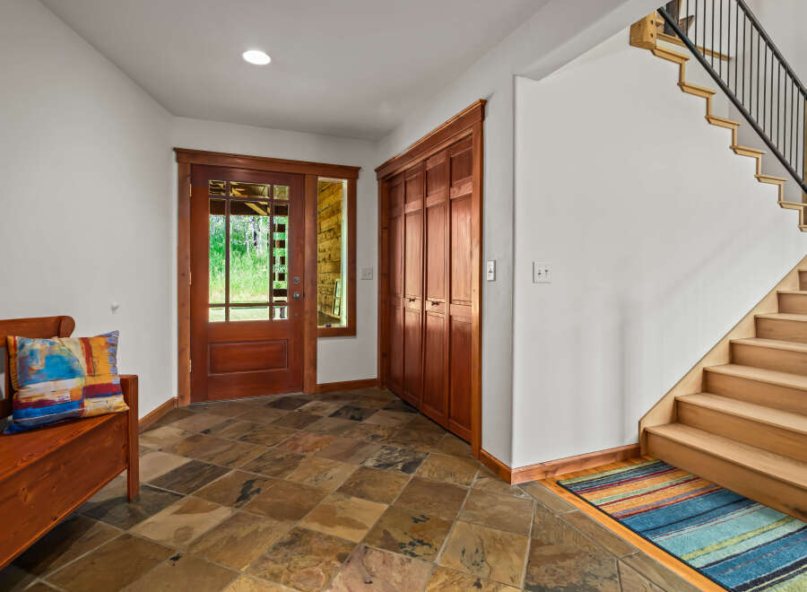 Step into this inviting entryway featuring a beautiful wooden bench with a colorful accent pillow, perfect for a warm welcome.