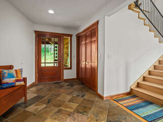 Step into this inviting entryway featuring a beautiful wooden bench with a colorful accent pillow, perfect for a warm welcome.