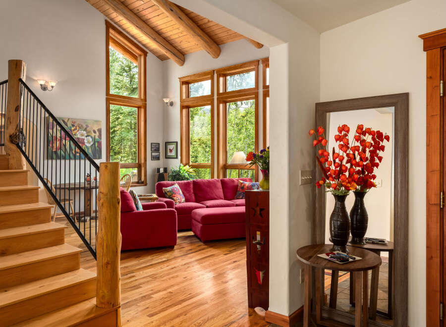 Experience rustic charm in this inviting living space featuring a grand wooden staircase and exposed beam ceiling.