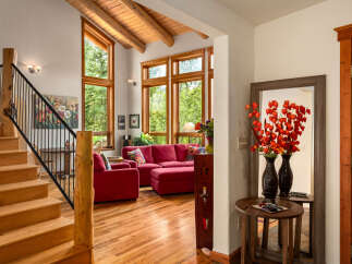 Experience rustic charm in this inviting living space featuring a grand wooden staircase and exposed beam ceiling.