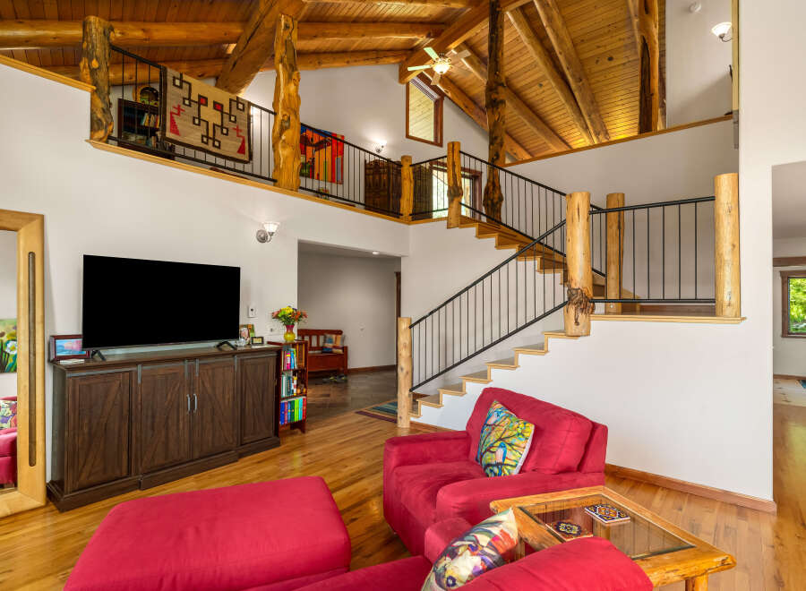 Experience rustic charm in this spacious living area featuring a soaring vaulted ceiling with exposed wooden beams and a loft overlooking the main floor.