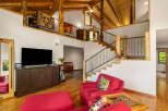 Experience rustic charm in this spacious living area featuring a soaring vaulted ceiling with exposed wooden beams and a loft overlooking the main floor.