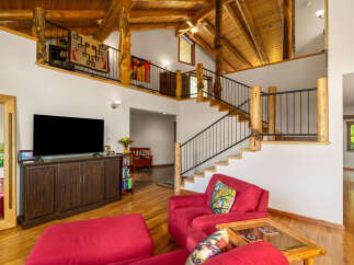 Experience rustic charm in this spacious living area featuring a soaring vaulted ceiling with exposed wooden beams and a loft overlooking the main floor.