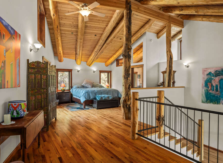 Experience rustic charm in this spacious loft bedroom featuring a vaulted wood-beam ceiling and a cozy seating area.