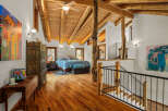 Experience rustic charm in this spacious loft bedroom featuring a vaulted wood-beam ceiling and a cozy seating area.