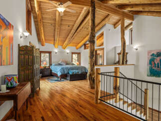 Experience rustic charm in this spacious loft bedroom featuring a vaulted wood-beam ceiling and a cozy seating area.