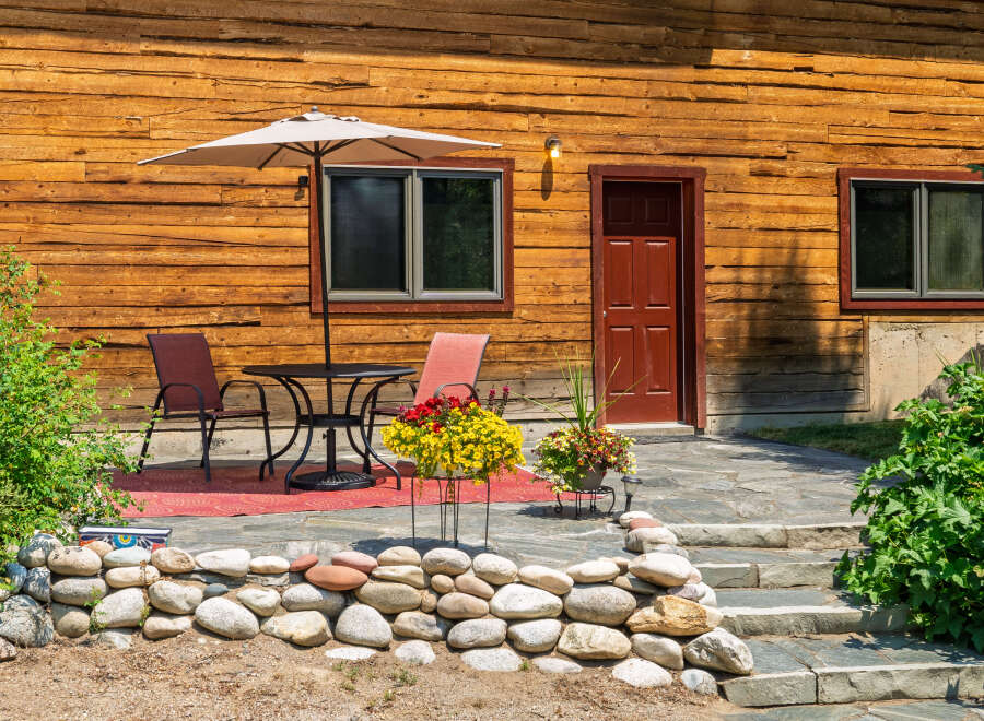 Enjoy outdoor living on this charming patio, complete with a table, chairs, and a large umbrella for shade.