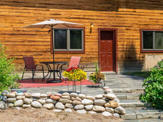 Enjoy outdoor living on this charming patio, complete with a table, chairs, and a large umbrella for shade.