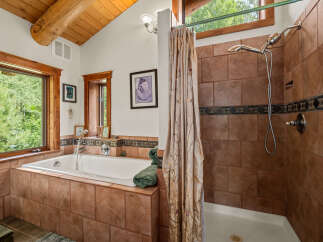 Experience tranquility in this rustic bathroom featuring a deep soaking tub surrounded by warm terracotta tiles and a separate shower with elegant tilework.