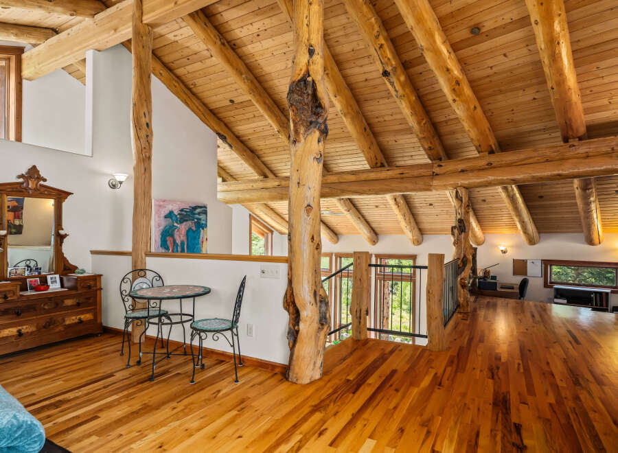 Experience rustic charm in this spacious loft featuring exposed log beams and a vaulted wood-paneled ceiling.