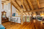 Experience rustic charm in this spacious loft featuring exposed log beams and a vaulted wood-paneled ceiling.