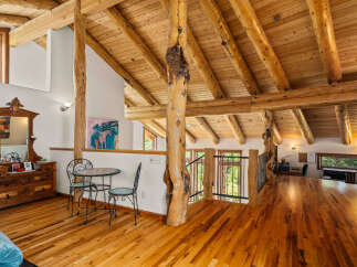 Experience rustic charm in this spacious loft featuring exposed log beams and a vaulted wood-paneled ceiling.