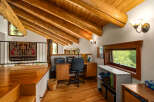 Discover a charming loft office space with rustic log beam accents and a vaulted wood-paneled ceiling.