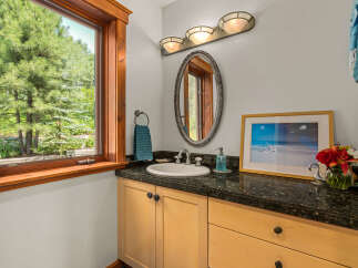 This charming bathroom features a spacious vanity with a granite countertop, a white porcelain sink, and elegant chrome fixtures.