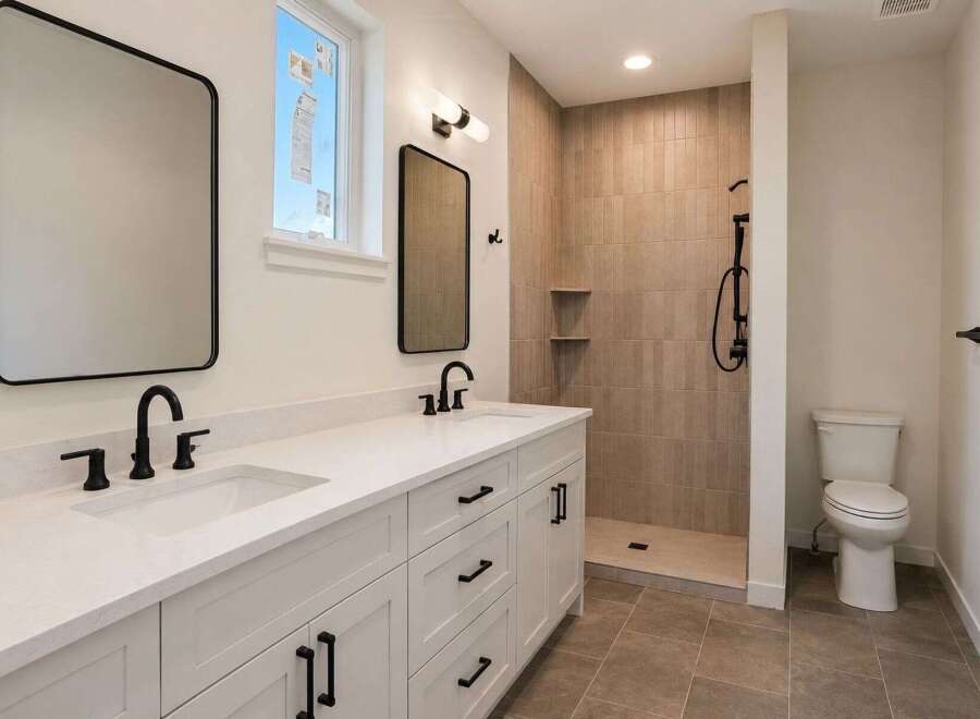This modern bathroom features a spacious double vanity with white quartz countertops and sleek black fixtures.