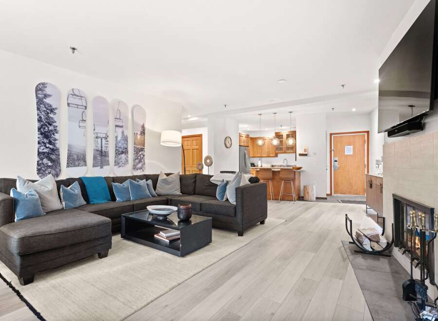 Experience modern mountain living in this stylish condo, featuring a spacious sectional sofa perfect for cozy evenings by the fireplace.