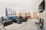 Experience modern mountain living in this stylish condo, featuring a spacious sectional sofa perfect for cozy evenings by the fireplace.