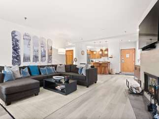 Experience modern mountain living in this stylish condo, featuring a spacious sectional sofa perfect for cozy evenings by the fireplace.
