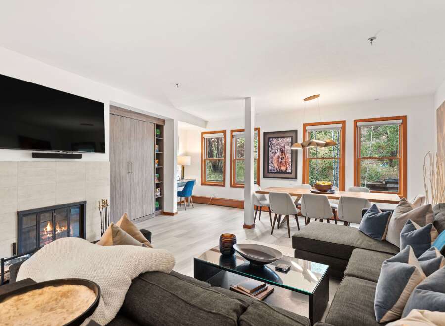 Experience modern living in this spacious open-concept home, featuring a cozy fireplace and a sleek wall-mounted TV.