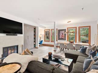 Experience modern living in this spacious open-concept home, featuring a cozy fireplace and a sleek wall-mounted TV.