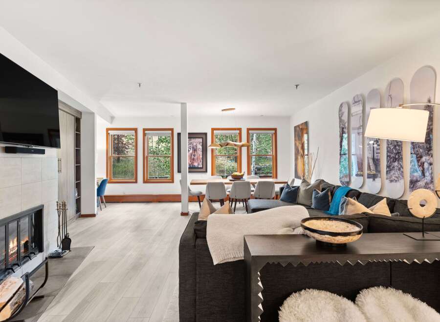 Experience modern mountain living in this spacious open-concept living area, featuring a cozy fireplace and a large sectional sofa perfect for gatherings.