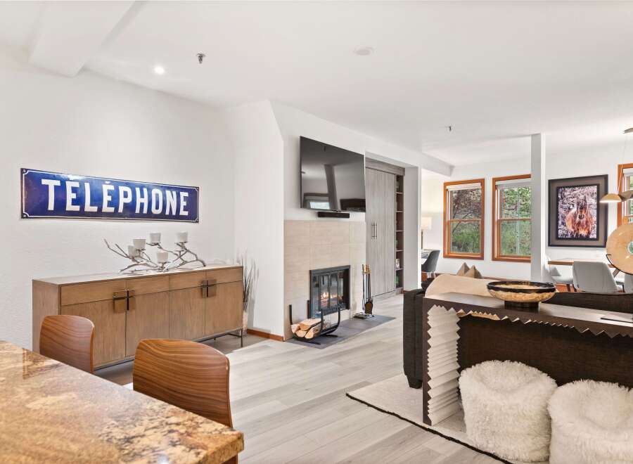 Experience modern living in this beautifully appointed living space, featuring a cozy fireplace and a stylish wooden credenza adorned with a unique candelabra.