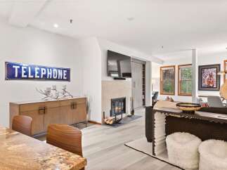 Experience modern living in this beautifully appointed living space, featuring a cozy fireplace and a stylish wooden credenza adorned with a unique candelabra.