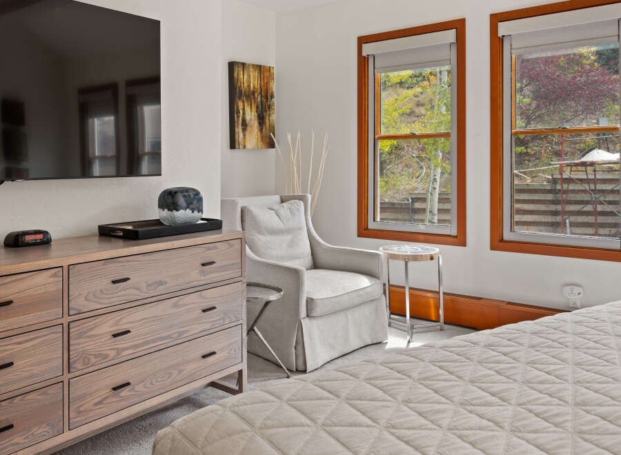 Experience comfort and style in this inviting bedroom, featuring a plush armchair perfect for relaxation and a modern dresser for ample storage.