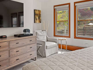 Experience comfort and style in this inviting bedroom, featuring a plush armchair perfect for relaxation and a modern dresser for ample storage.