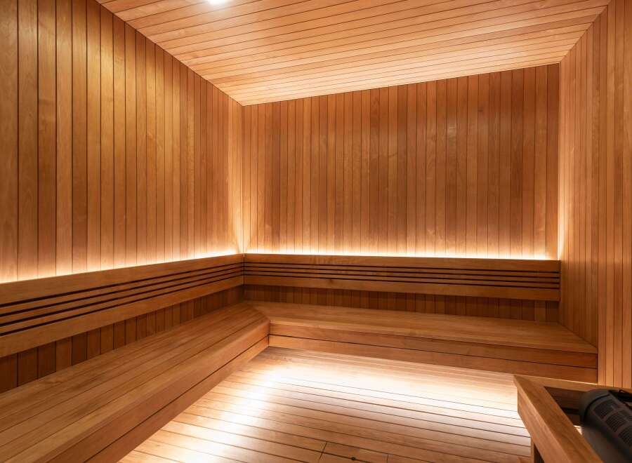 Experience ultimate relaxation in this luxurious wooden sauna, featuring multi-level seating and ambient lighting.