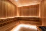 Experience ultimate relaxation in this luxurious wooden sauna, featuring multi-level seating and ambient lighting.