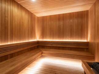 Experience ultimate relaxation in this luxurious wooden sauna, featuring multi-level seating and ambient lighting.