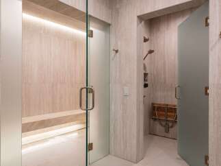 Experience ultimate relaxation in this luxurious spa-like bathroom featuring a spacious steam room with a built-in bench and ambient lighting.
