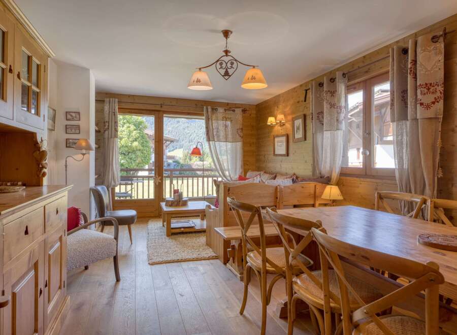 Experience cozy mountain living in this charming wooden chalet, featuring a spacious dining area with a large wooden table and chairs, perfect for family meals.
