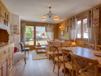 Experience cozy mountain living in this charming wooden chalet, featuring a spacious dining area with a large wooden table and chairs, perfect for family meals.